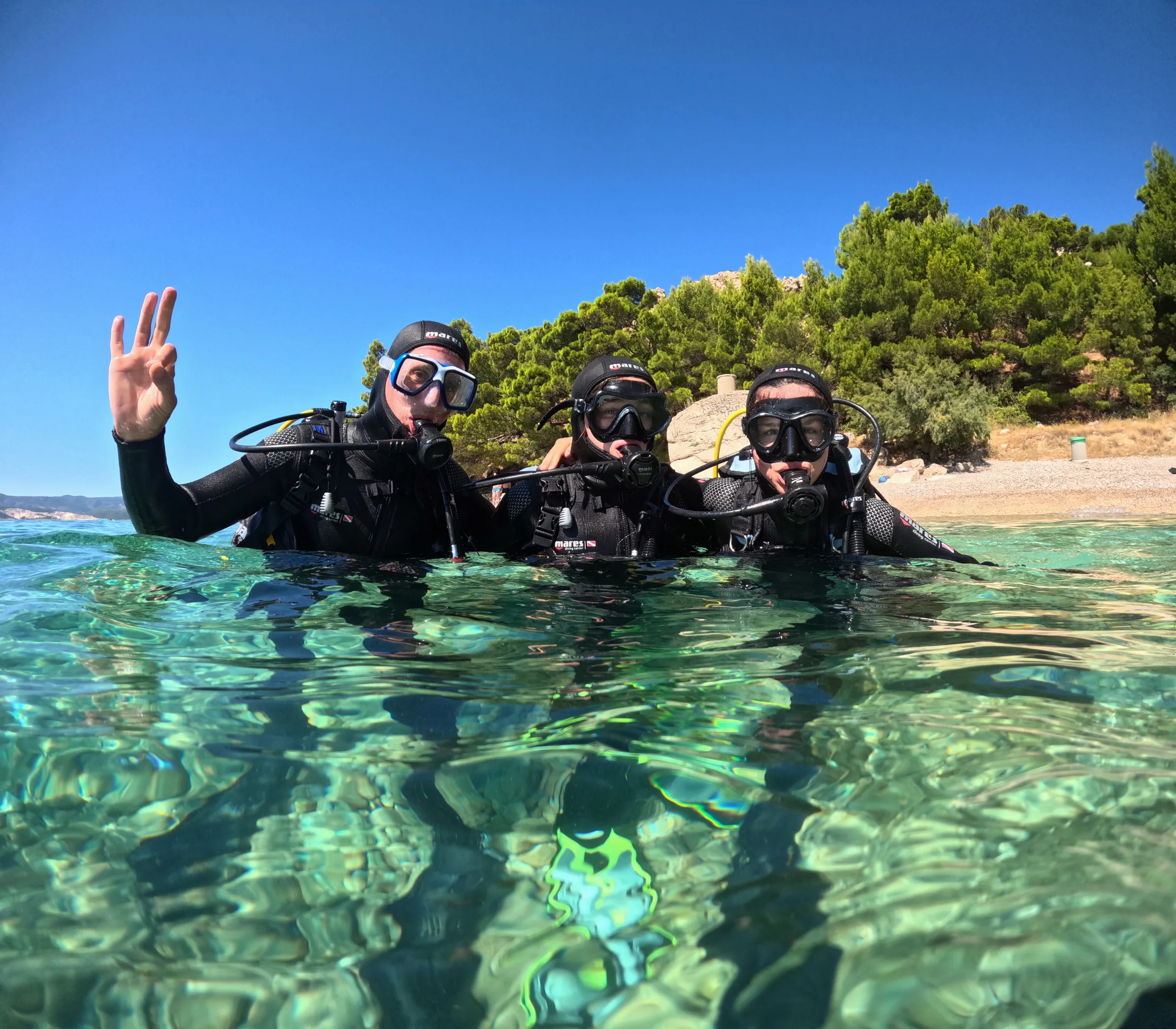 Small group of smiling divers at the surface with the Omis coastline behind